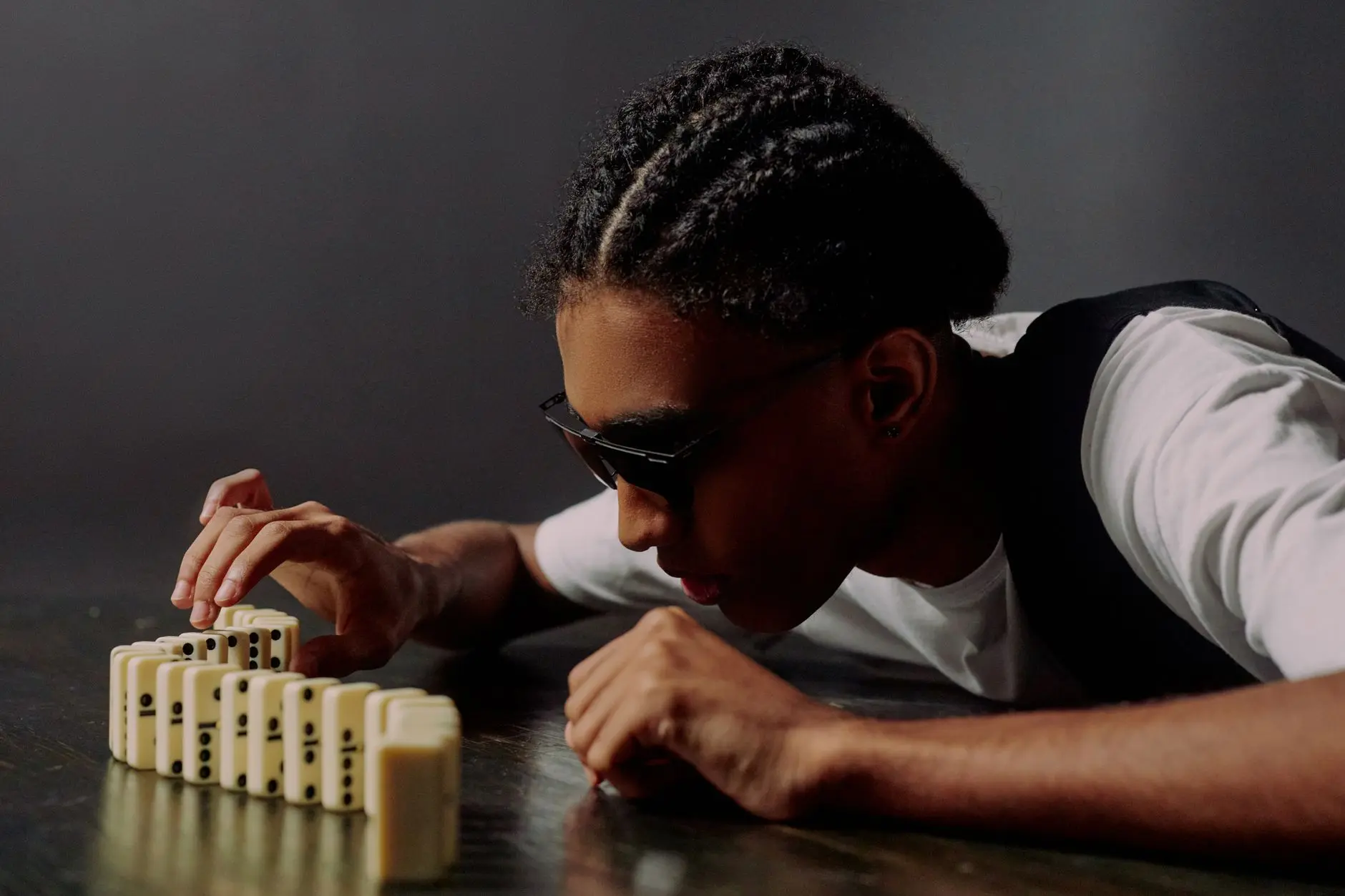 A row of dominoes with the first one starting to fall, captured in natural light.